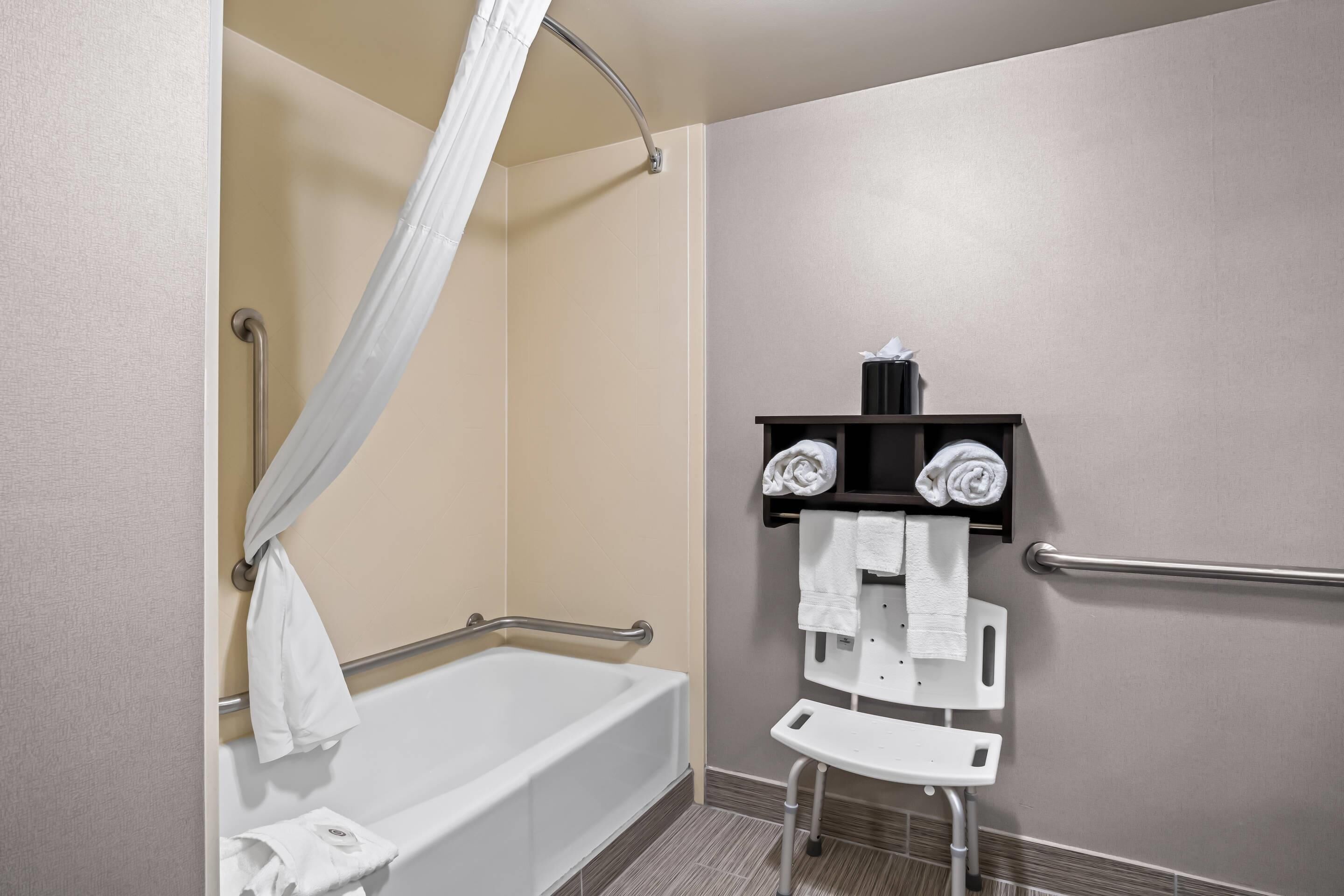 Ein Badezimmer mit einer Badewanne, einer Duschvorhang, einem Handtuchhalter und einer Haltestange.