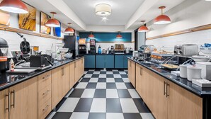 A modern kitchen with checkered flooring, wooden cabinets, and red pendant lighting.