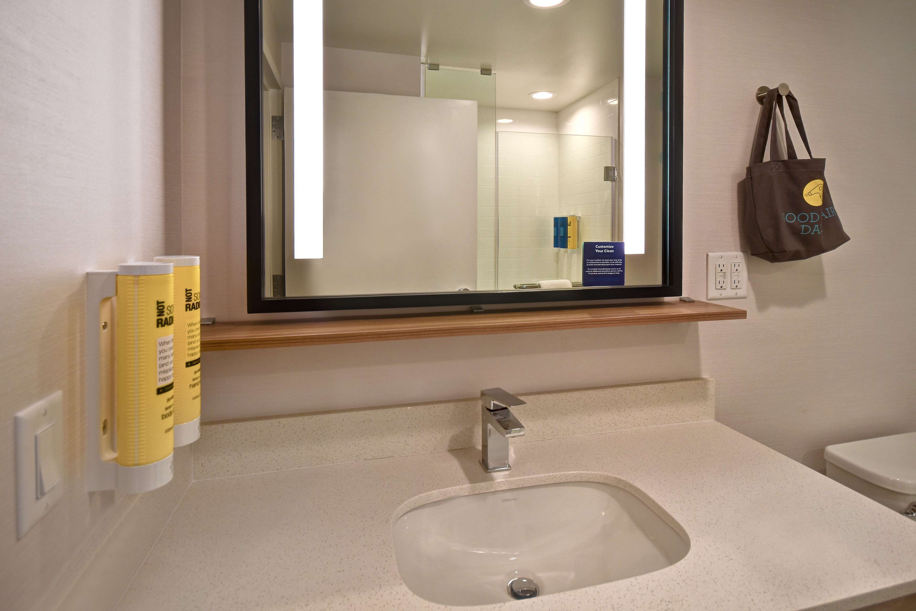 A bathroom with a sink, mirror, and toiletries.