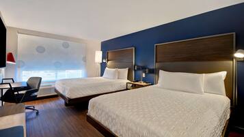 A hotel room with two beds, a desk, and a chair.