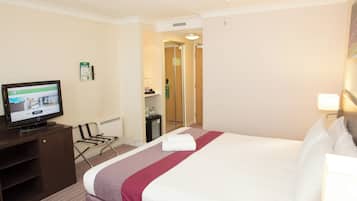 A hotel room with a bed, a television, a desk, and a chair.
