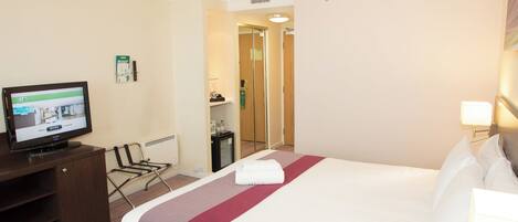 A hotel room with a bed, a television, a desk, and a chair.