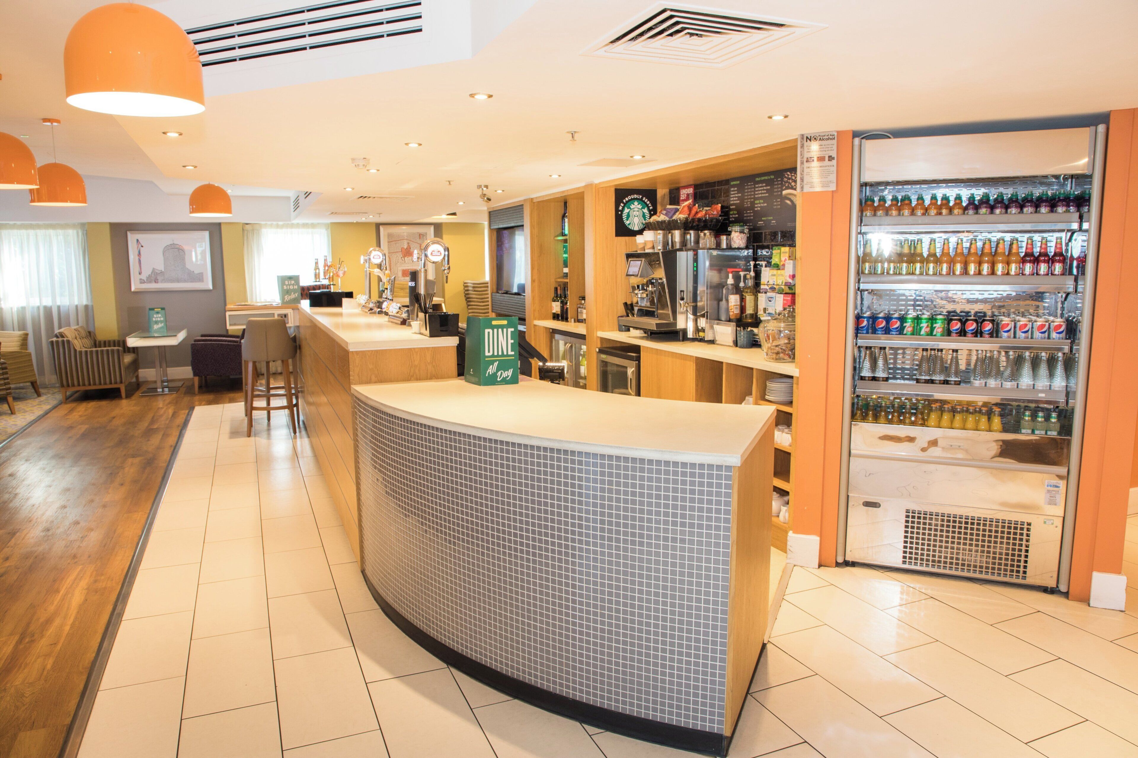 A bar area with a counter, seating, and a refrigerator stocked with beverages.