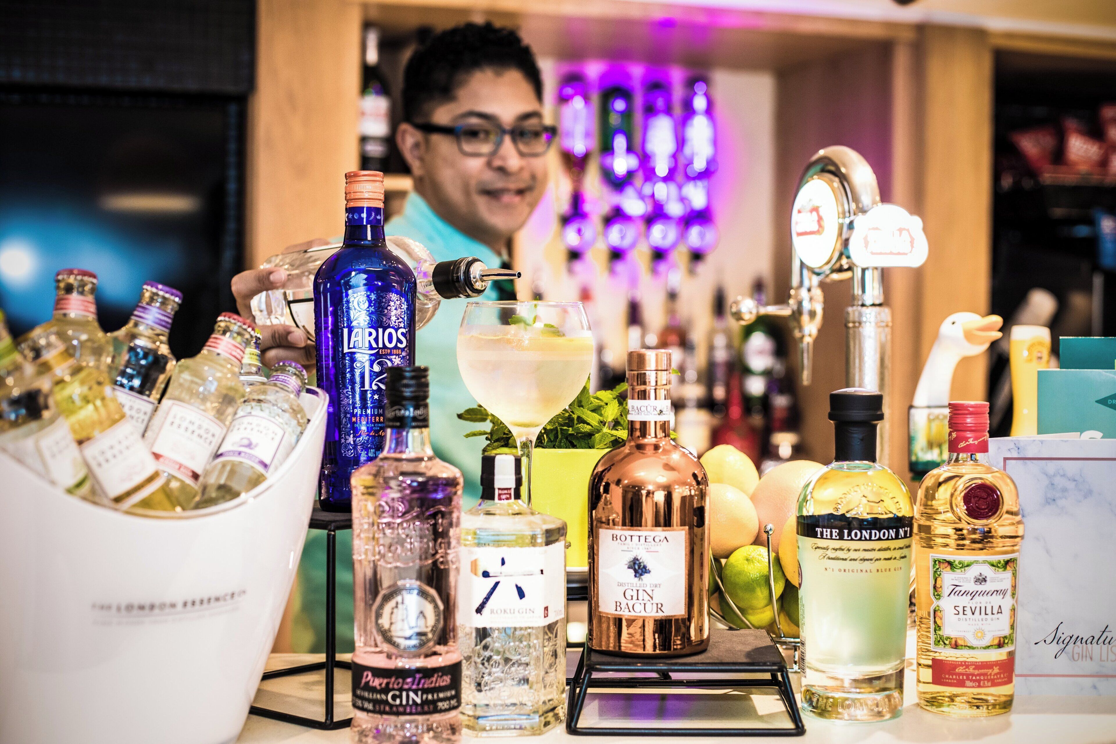 Eine Bar mit verschiedenen Spirituosen, einem Barkeeper und einem zubereiteten Cocktail.