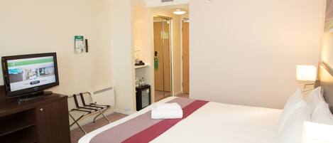 A hotel room with a bed, a television, a desk, and a wardrobe.
