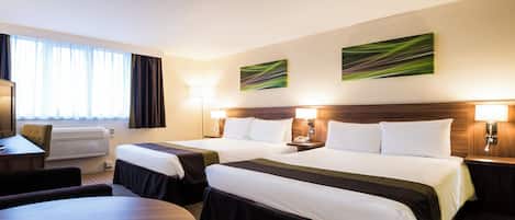 A hotel room with two beds, a desk, a chair, a round table, and a window with curtains.