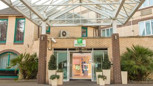 A Holiday Inn hotel with a glass entrance, brick facade, and green-framed windows. - Holiday Inn Slough - Windsor by IHG (Slough)