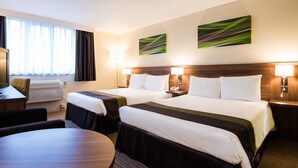 A hotel room with two beds, a desk, a chair, and a round table. - Holiday Inn Slough - Windsor by IHG (Slough)