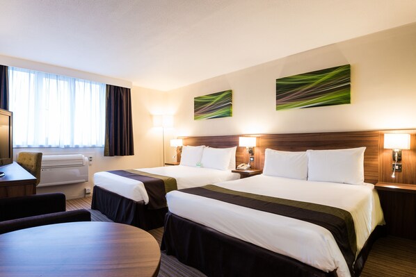 A hotel room with two beds, a desk, a chair, and a round table. - Holiday Inn Slough - Windsor by IHG (Slough)