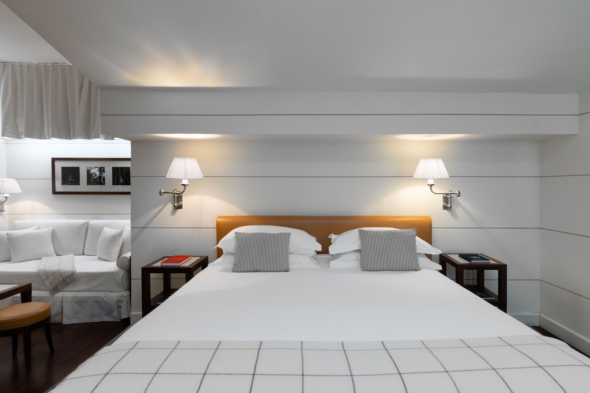 A hotel room with a large bed, two bedside tables, a chair, and a wall-mounted lamp.