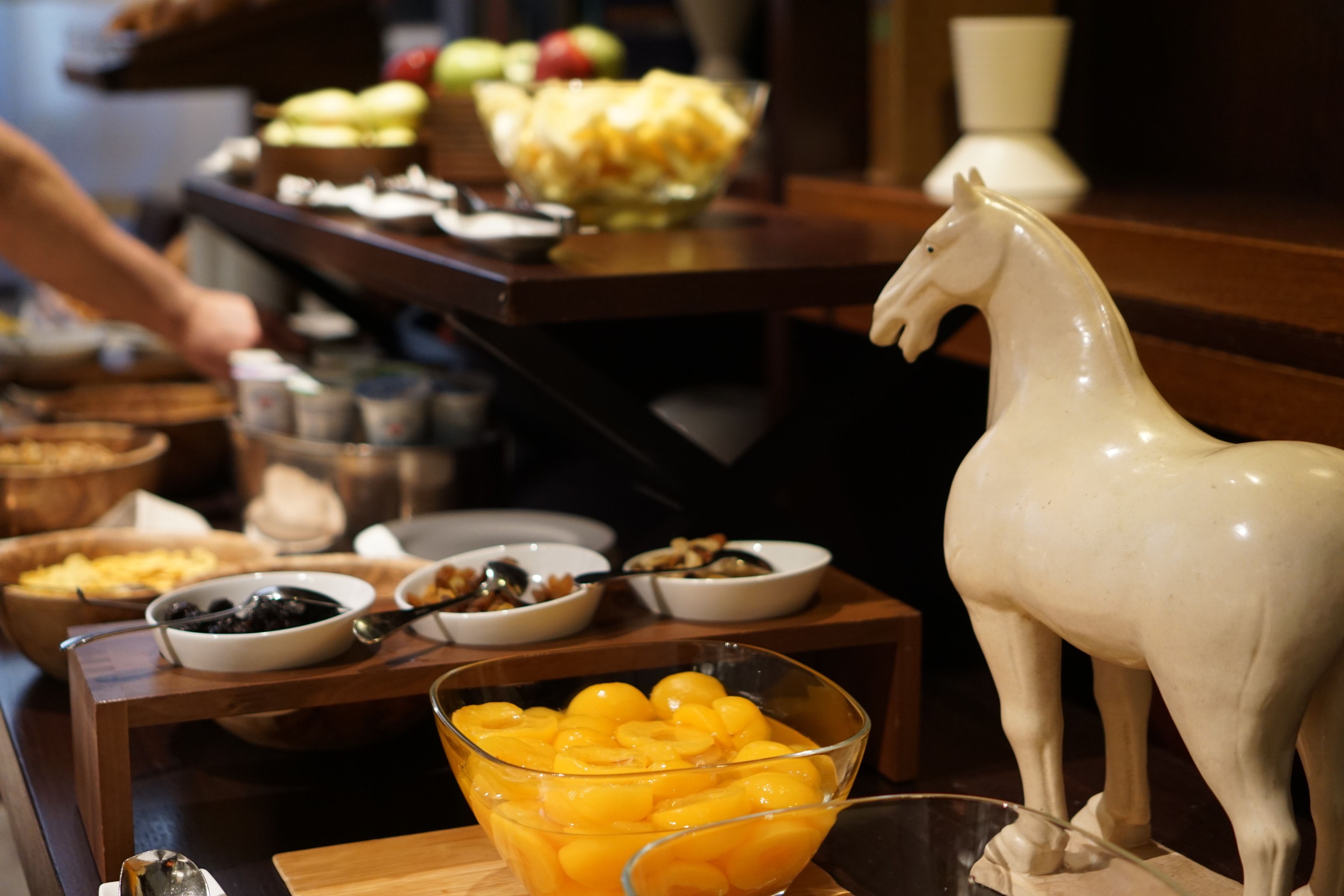 Una mesa de buffet con diversos alimentos y una estatua de un caballo blanco.