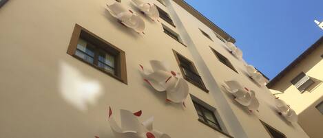 A building facade with multiple windows and decorative paper flowers.