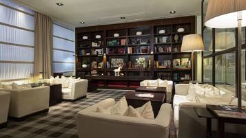 A modern living room with a large bookshelf, comfortable seating, and a large window.