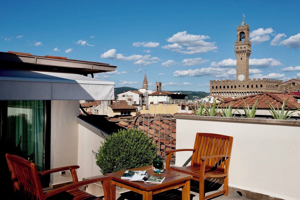 A balcony with a table, chairs, and a view of a historic tower.