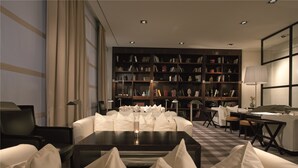 A modern library with a large bookshelf, a sofa, and a table with a candle. - Gallery Hotel Art - Lungarno Collection (Florence)