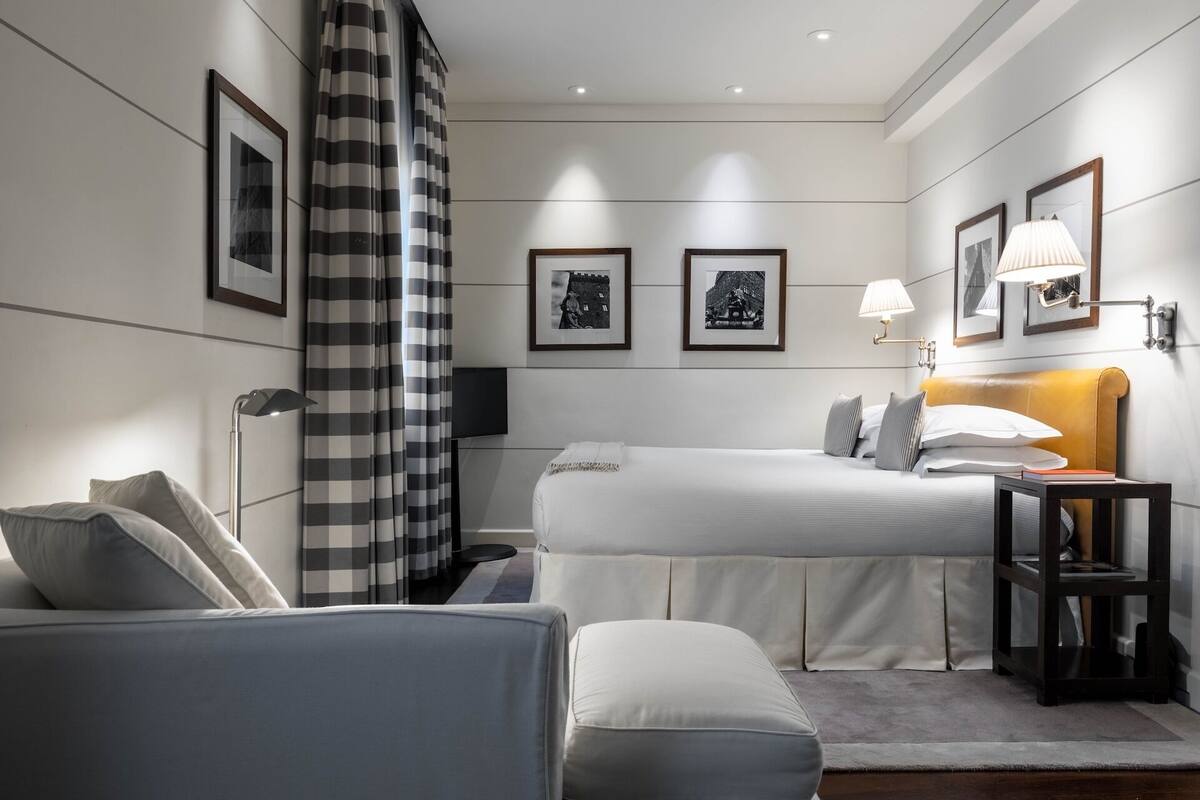 A modern hotel room with a bed, a sofa, a small table, and a TV.