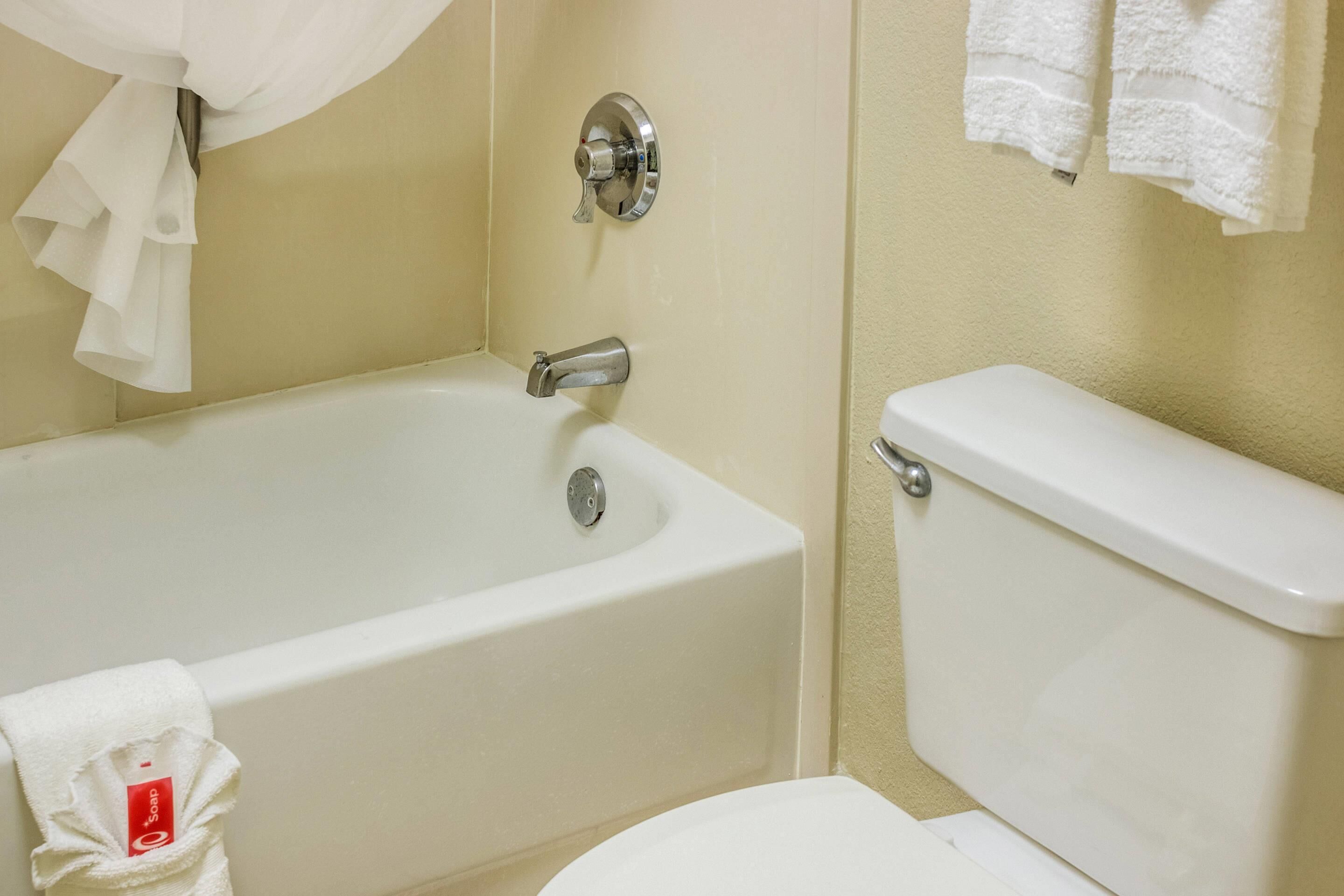 A bathroom with a bathtub, toilet, and a towel rack with towels.