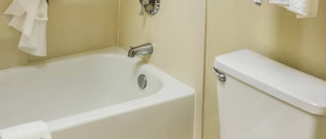 A bathroom with a bathtub, toilet, and a towel rack with towels.