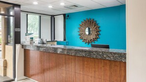 Mostrador de recepción con pared azul, un mueble de madera, un espejo y una ventana con persianas.