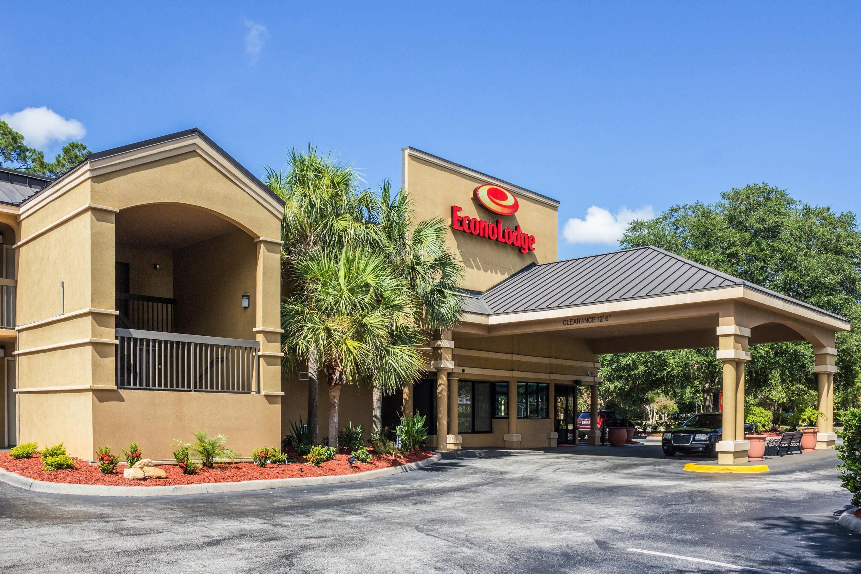 Un hotel Target con entrada techada, palmeras y estacionamiento.