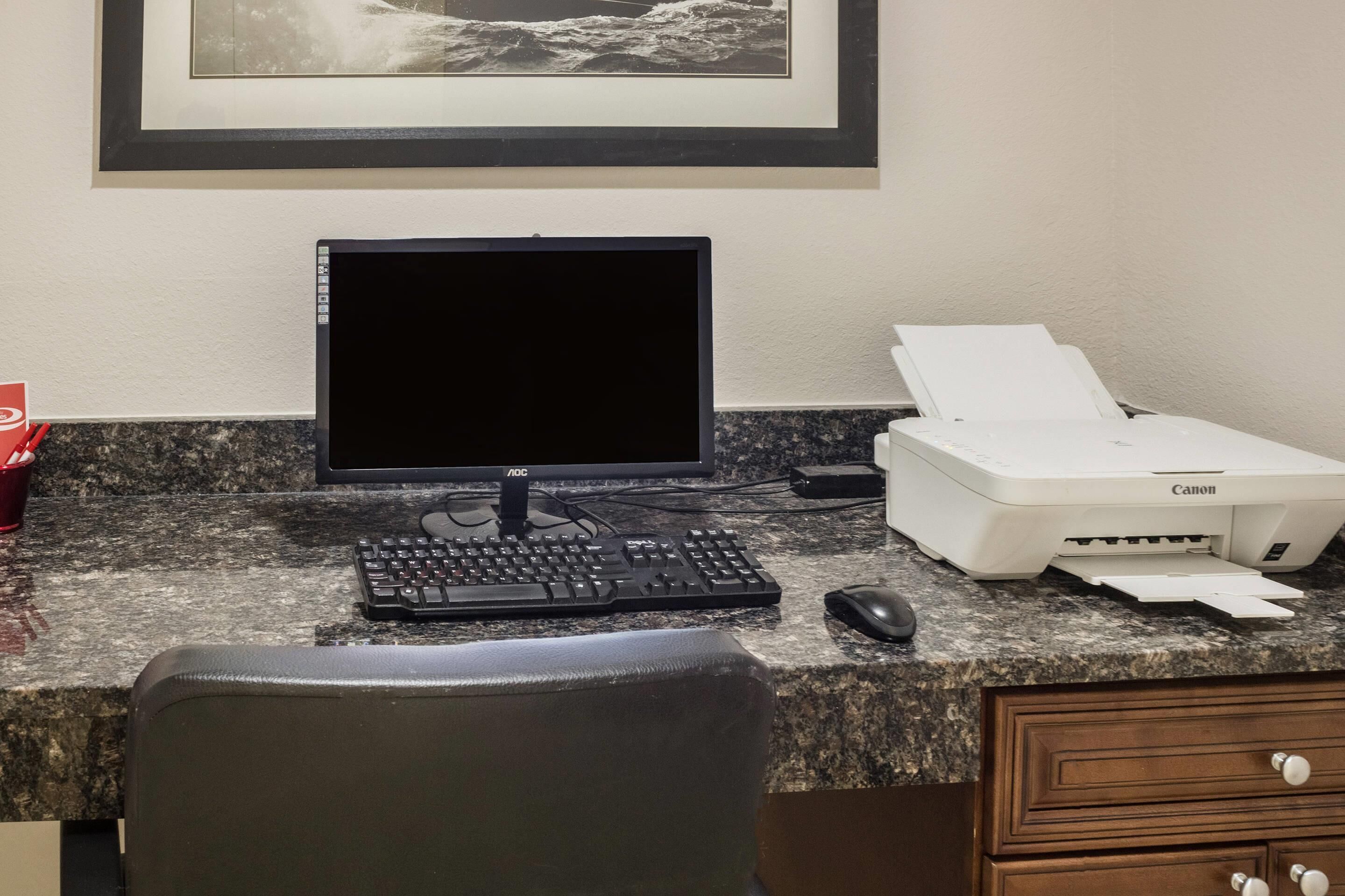 A workspace with a desktop computer, keyboard, mouse, and printer on a granite countertop.