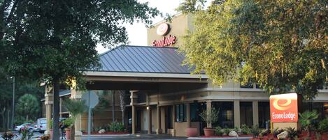 A hotel entrance with a covered walkway, a sign reading "EconoLodge," and a parking lot with cars.