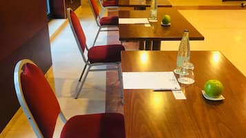 A conference room with wooden tables and red upholstered chairs.