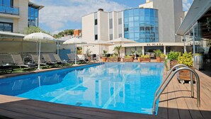 Un hotel moderno con piscina, tumbonas y sombrillas.