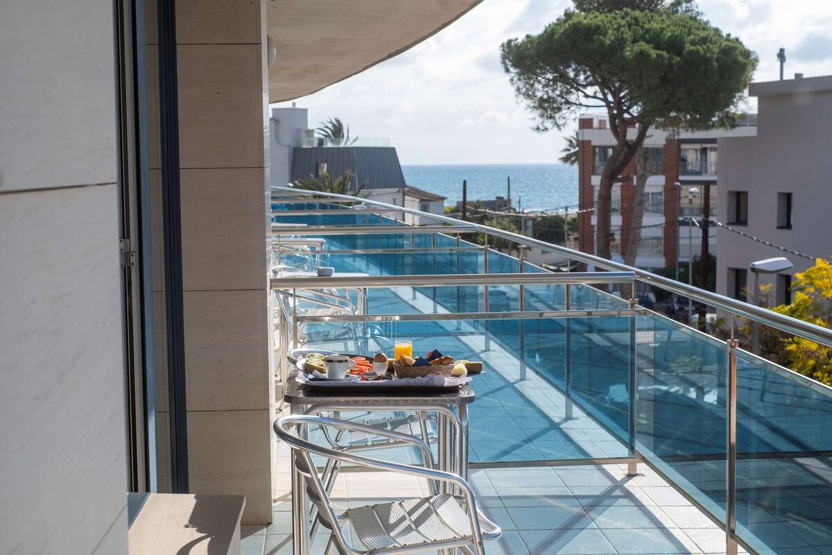 Un balcon doté d’une balustrade en verre, offrant une vue sur une piscine et la mer.