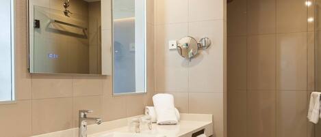 A modern bathroom with a large mirror, a sink, a shower, and a toilet.