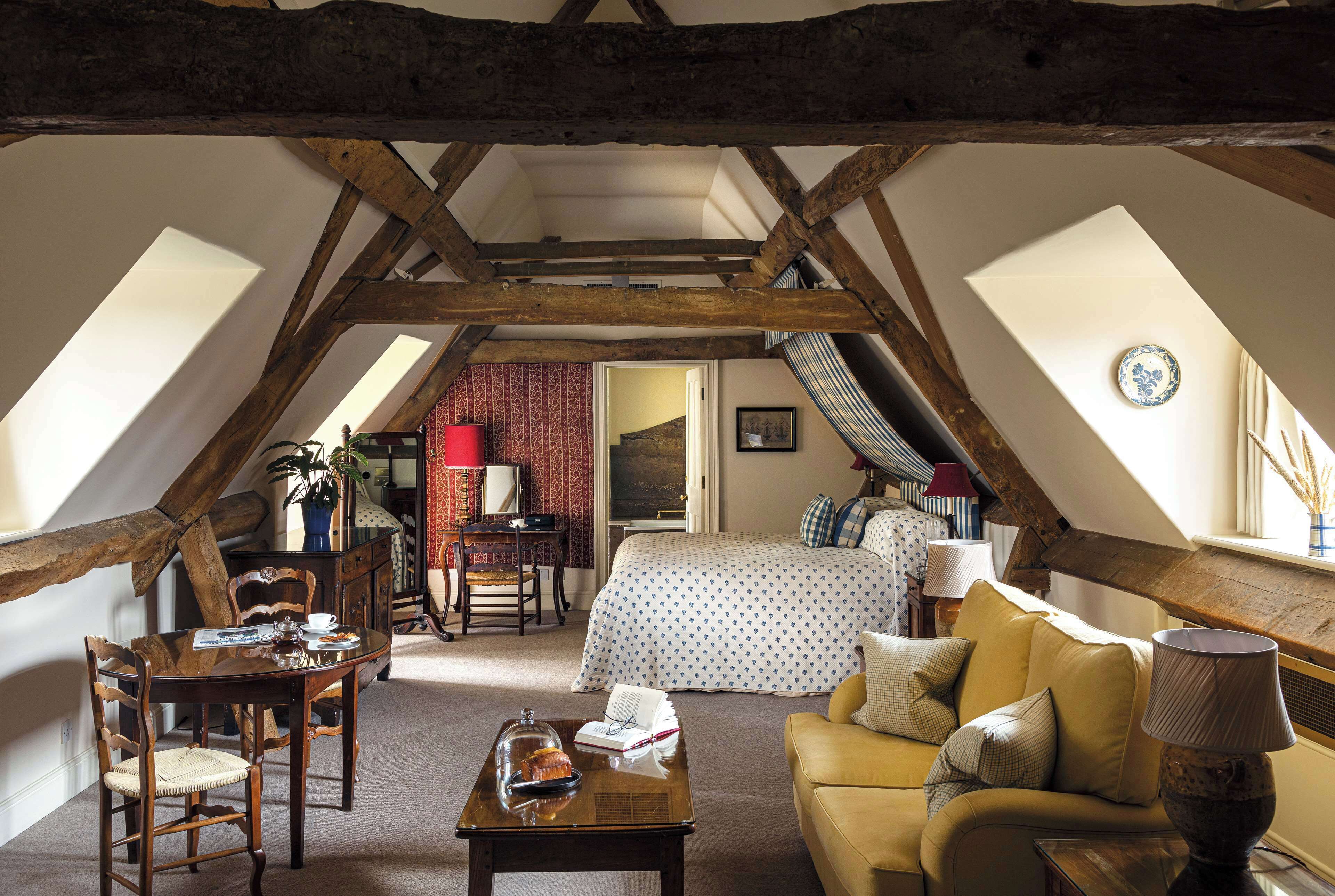 Une chambre confortable située sous les toits, avec un lit, un canapé et une table à manger.