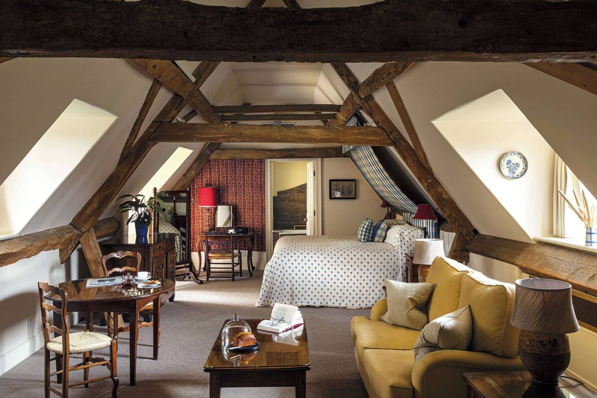 A cozy attic bedroom with a bed, sofa, and dining table.