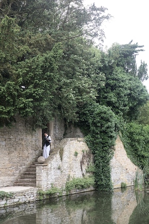 Un escalier en pierre menant à un plan d’eau, entouré d’une végétation luxuriante et d’arbres.