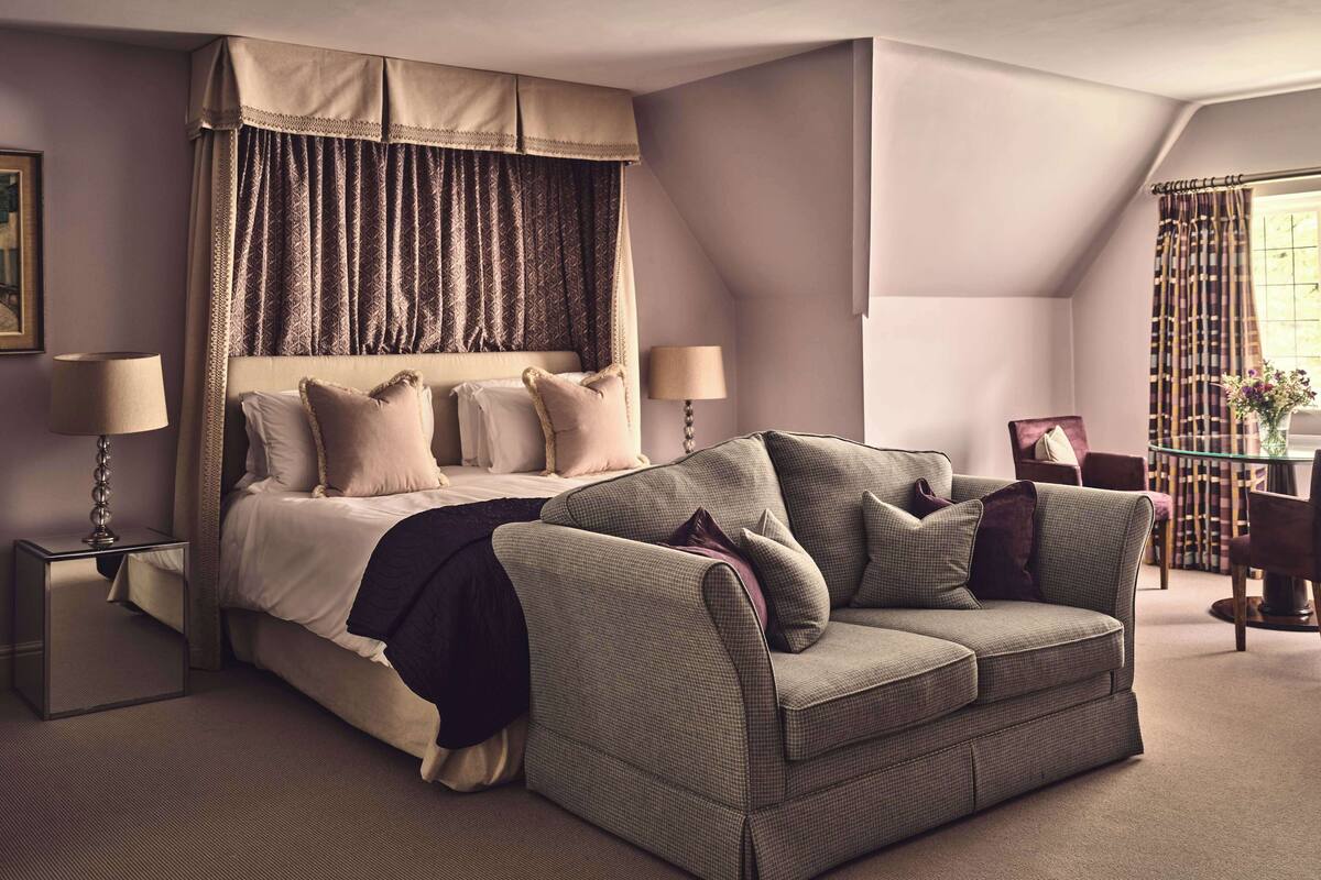 A bedroom with a large bed, two bedside tables, a sofa, and a chair.