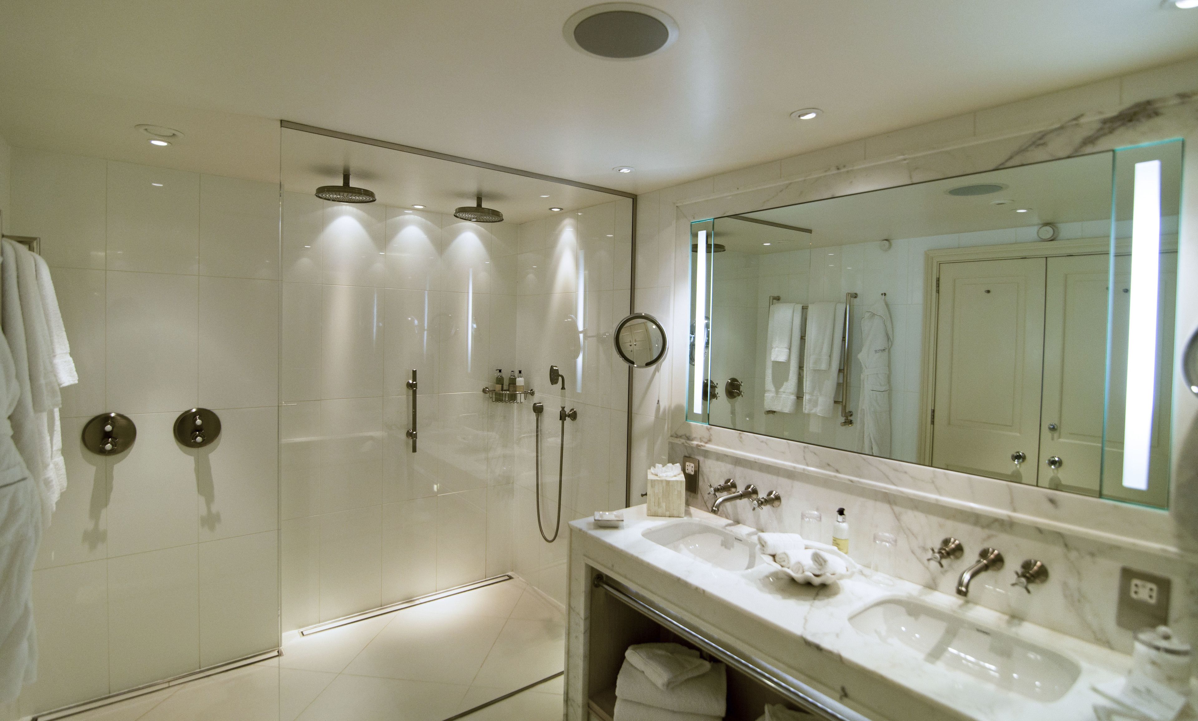 A modern bathroom with a glass-enclosed shower, a large mirror, and a dual sink vanity.