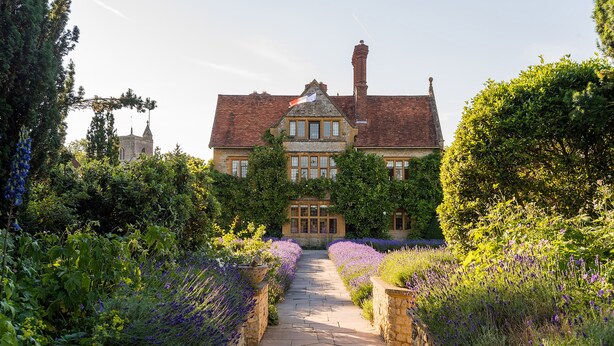 Un bâtiment historique doté d’une cour intérieure, de murs en pierre et d’une grande variété de plantes à fleurs.