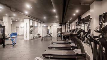 Un gimnasio con cintas de correr, máquinas de pesas y bancos.