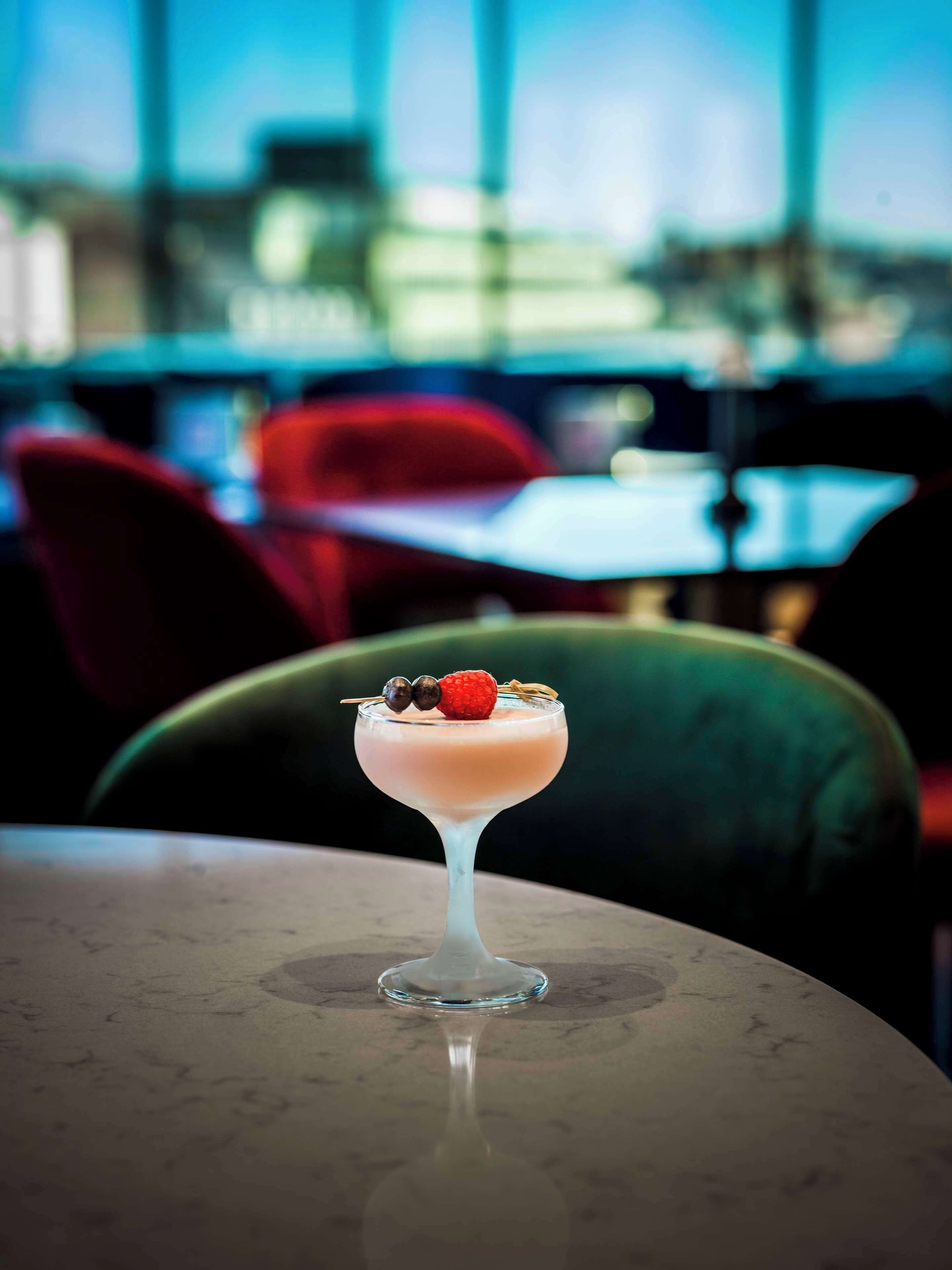 A cocktail in a glass on a table with a blurred background of a restaurant interior.