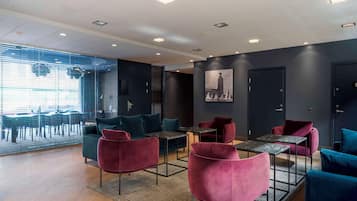A modern lounge area with seating, tables, and a cityscape view.