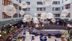 En rymlig innergård med flera matplatser, stora, dekorativa, sfäriska lampor och en central sittgrupp med utsikt över den omgivande byggnaden.