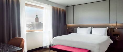 Ein Hotelzimmer mit einem großen Bett, einem Schreibtisch und einer Sitzbank.