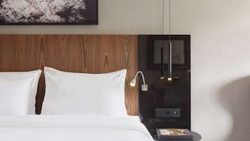 Une chambre d’hôtel avec un grand lit, une tête de lit en bois, une table de chevet avec une lampe et un tableau encadré au mur.