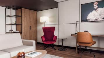 Una sala de estar moderna con un sofá, un sillón rojo, una mesa de centro, un televisor montado en la pared y un mueble de madera.