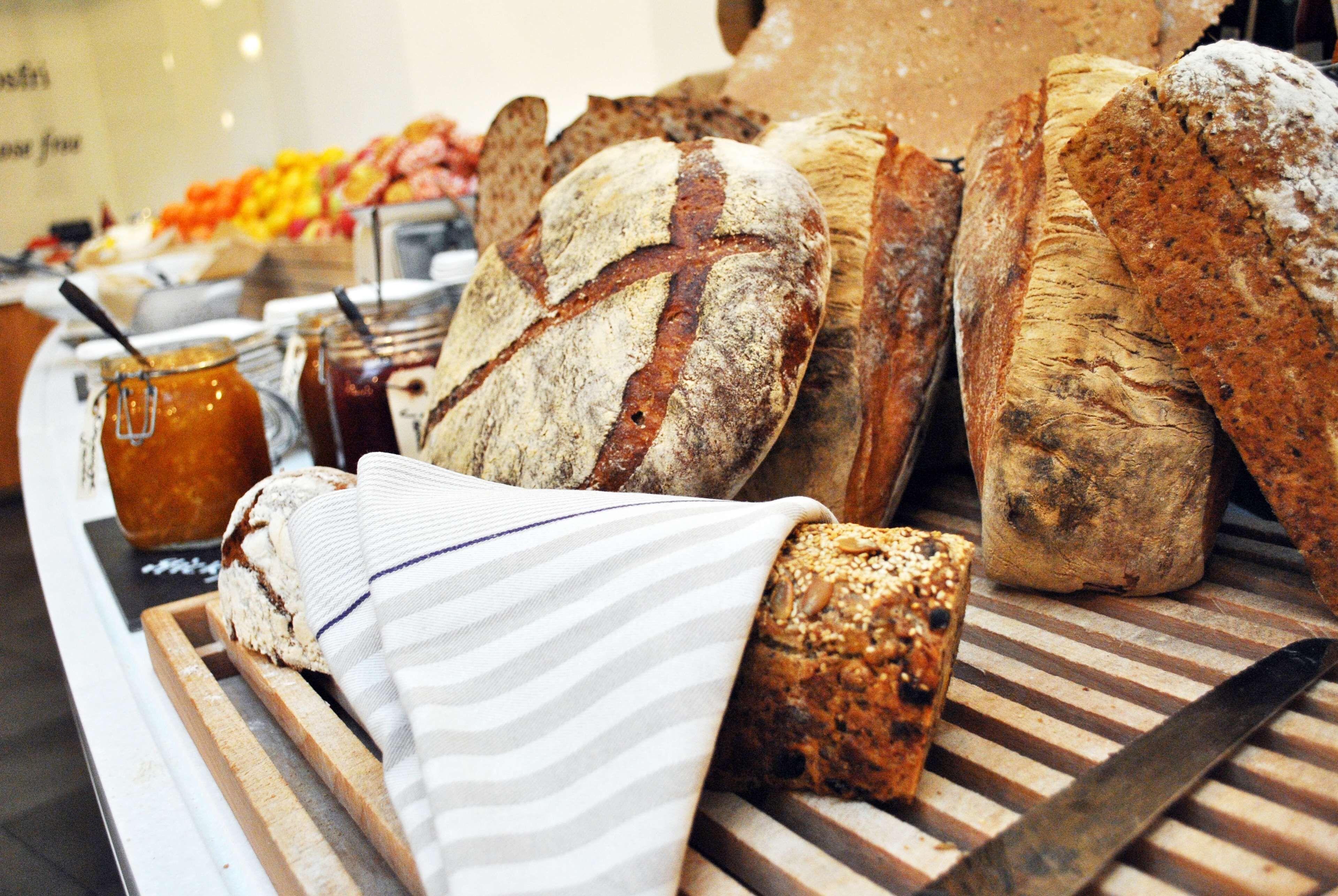A variety of breads and pastries on a wooden board with a striped cloth.