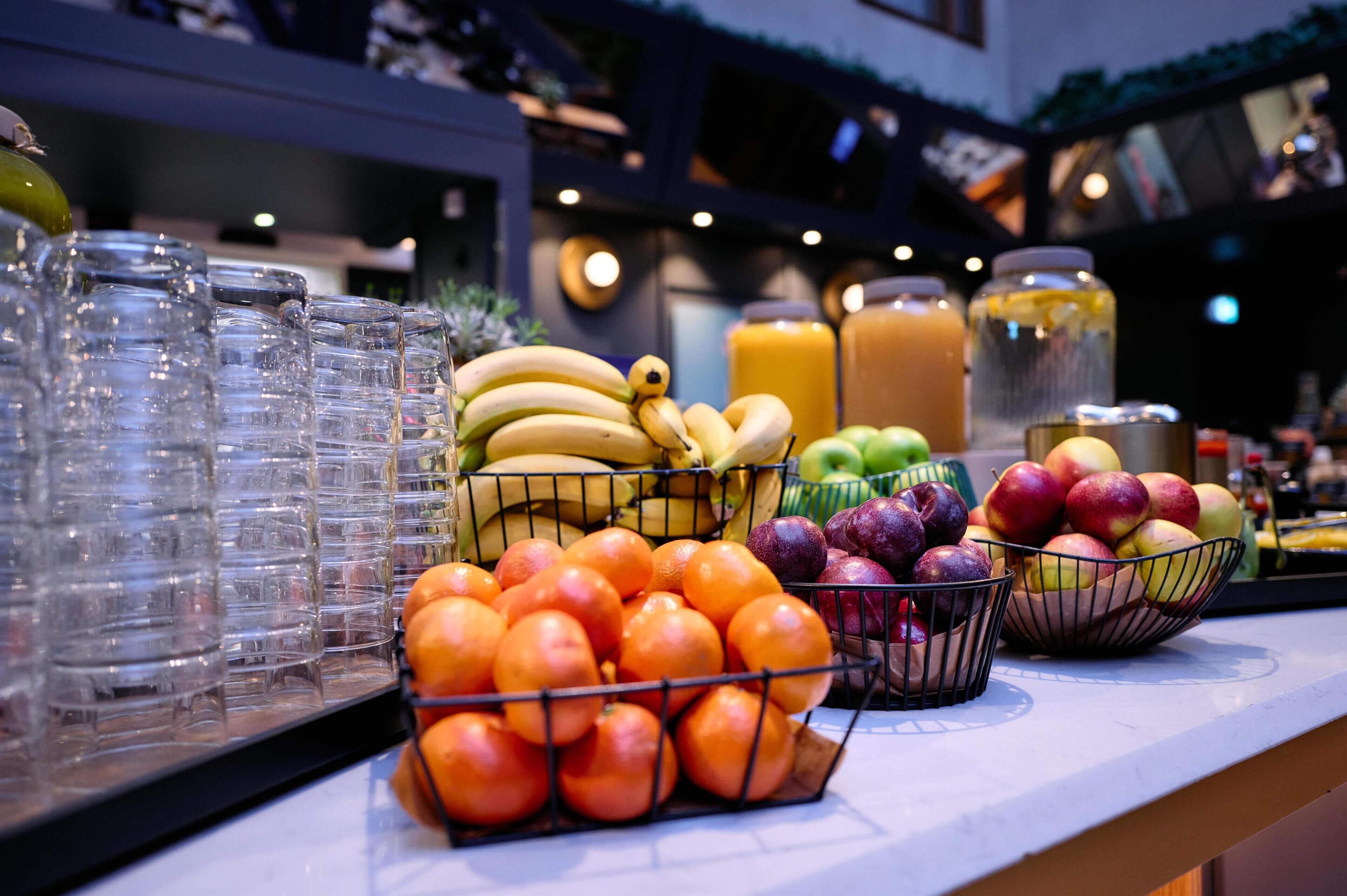 A breakfast bar with various fruits and beverages.