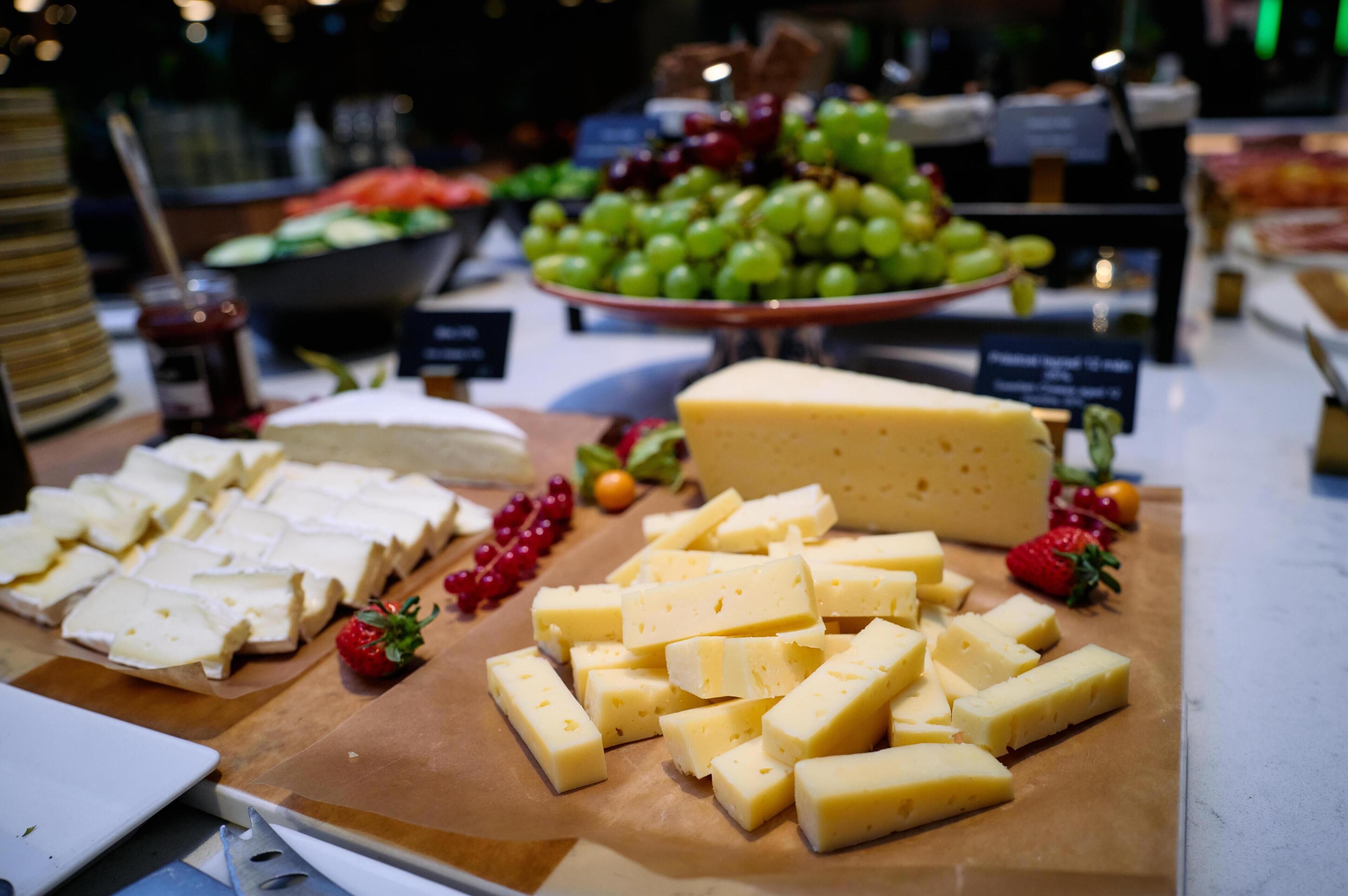 A cheese and fruit display with various types of cheese and grapes.