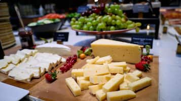 A cheese and fruit display with various types of cheese and grapes.