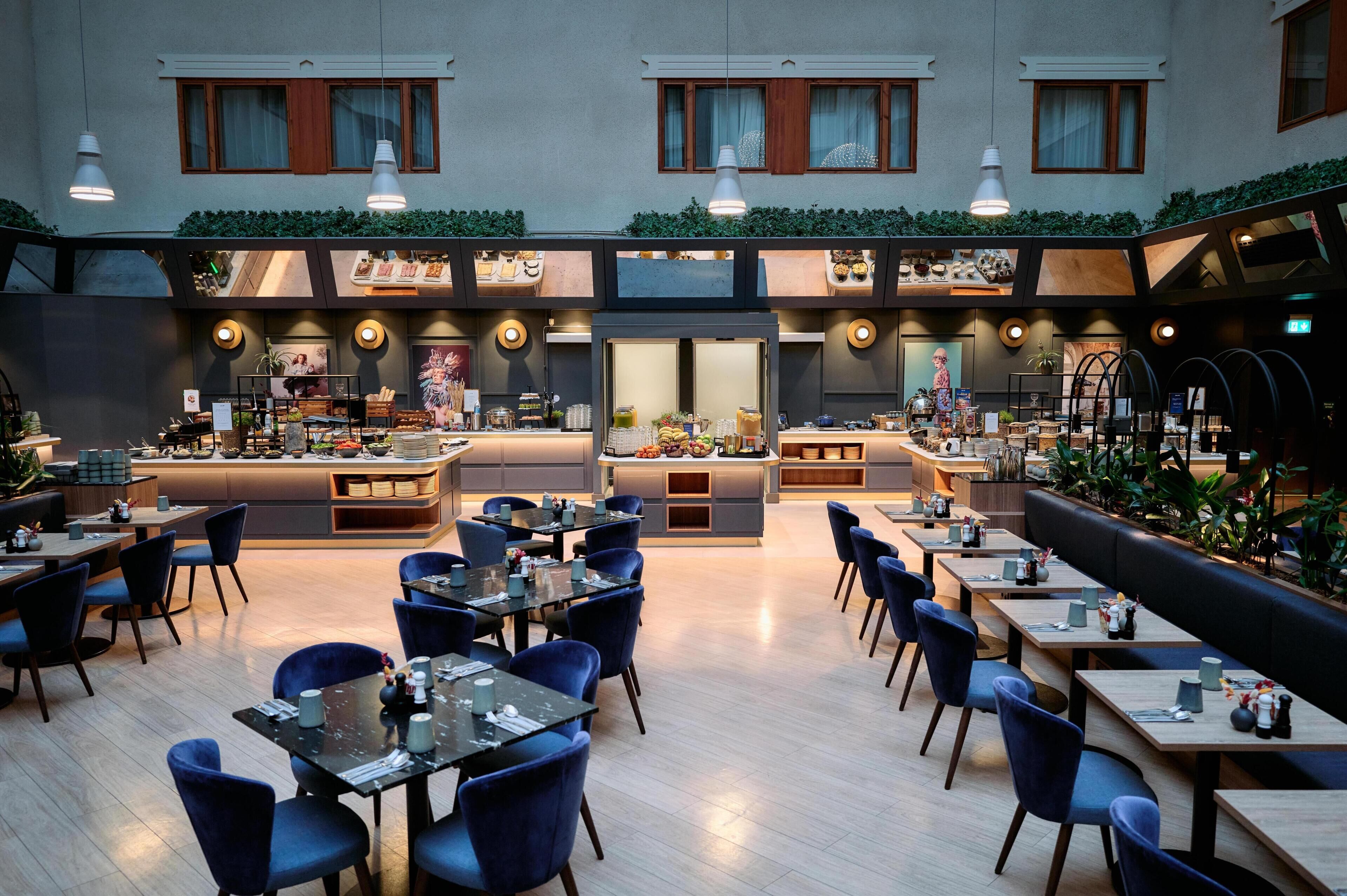 Un restaurante moderno con barra central, varias zonas de estar y vistas a la ciudad.