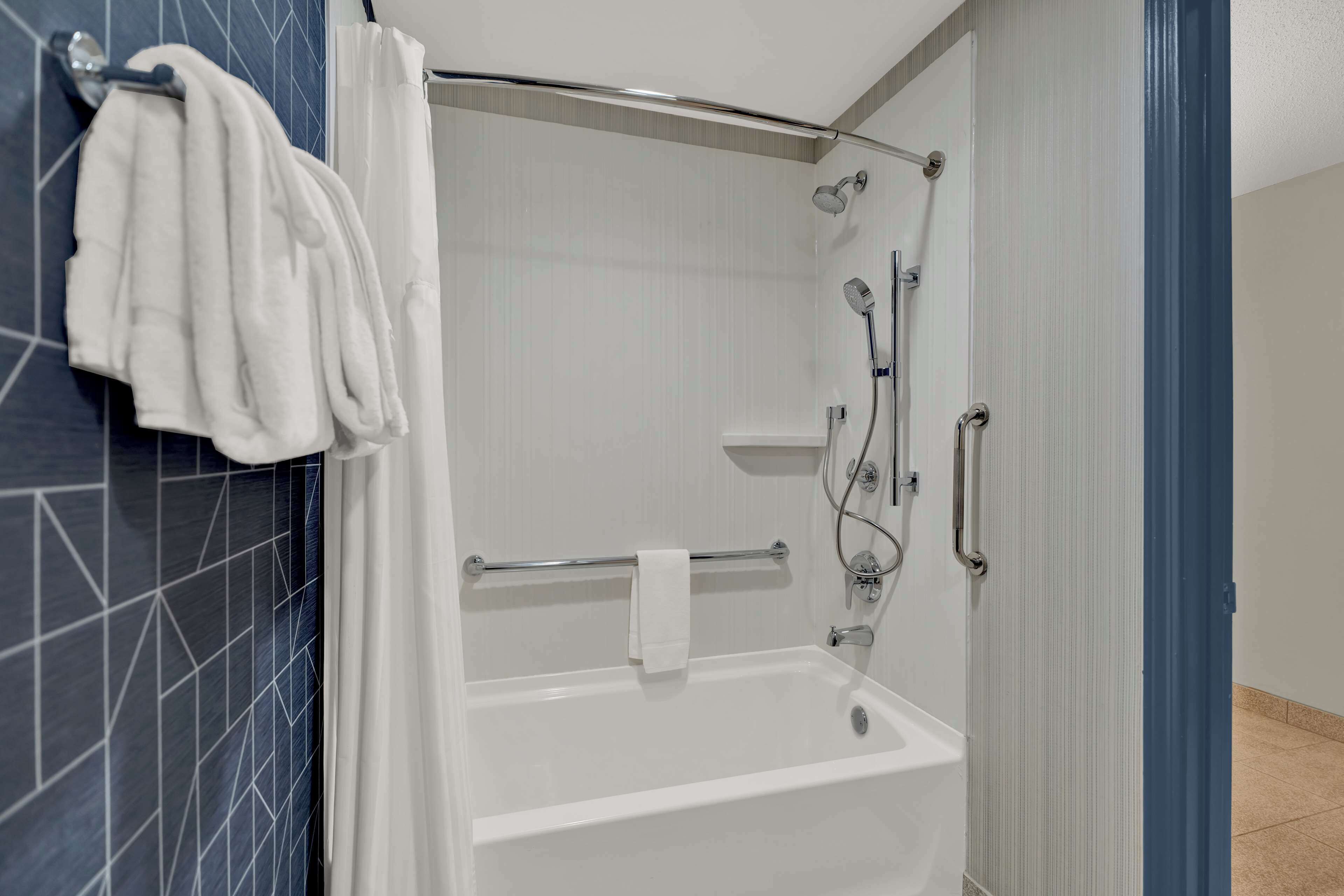 Un baño moderno con bañera, ducha y toallero.
