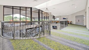 A spacious lobby with a curved railing, a staircase, and a chandelier. - Spark by Hilton Plymouth (Plymouth)